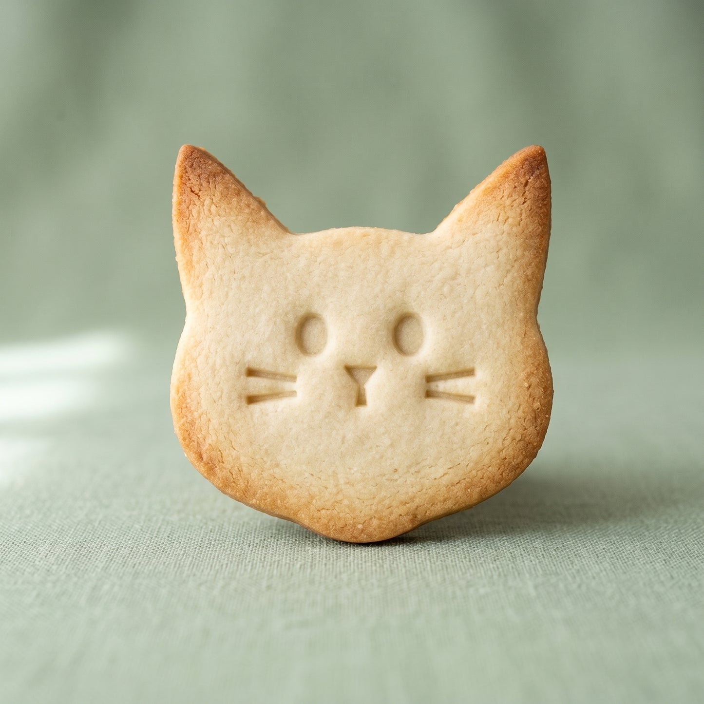 Cat face shaped sugar cookie with embossed eyes, nose, and whiskers