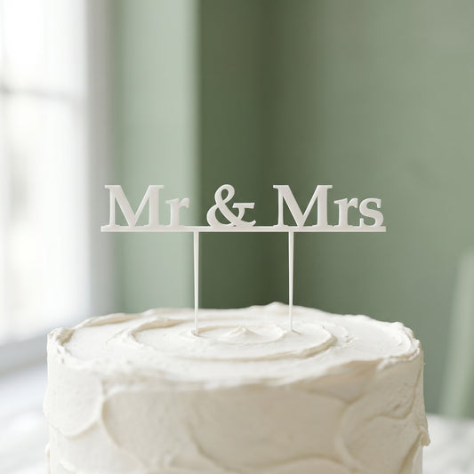 Mr and Mrs white cake topper standing on a frosted wedding cake
